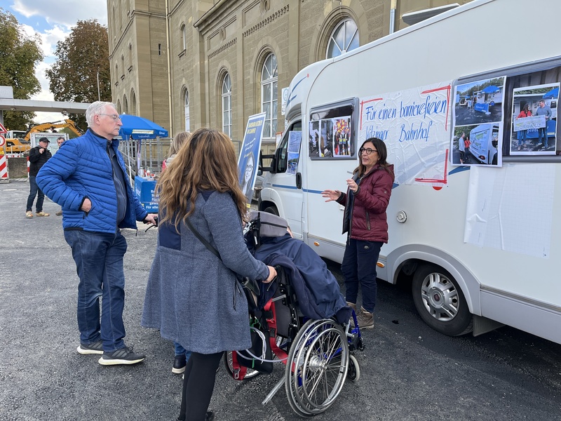 Am Camper vor dem Kitzinger Bahnhof erklärt Barbara Becker Betroffenen und Interessierten, was in den letzten Jahren bereits erreicht wurde  und warum sie beim Thema Barrierefreiheit weiter dranbleibt.